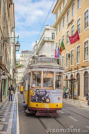 Very touristic place in the old part of Lisbon, with a traditional tram passing by in the city of Lisbon, Portugal. Editorial Stock Photo